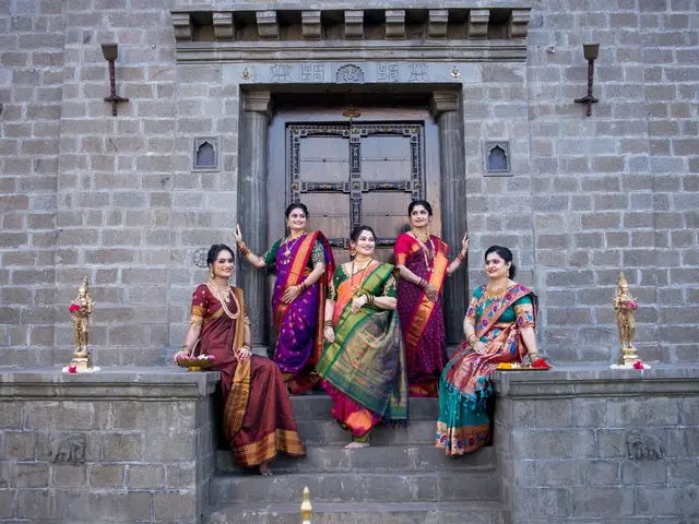 Women in traditional Maharashtrian sarees gathered on the stone threshold of the grand carved Mahadwar.