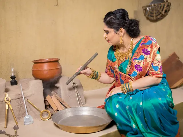 Traditional hearth cooking setup with copper utensils, blowing pipe, and clay stove in the wada kitchen.