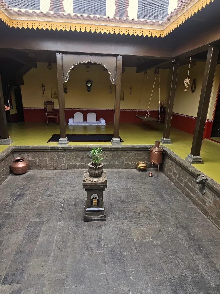The open central courtyard at Gundal Wada, sunken and stone-paved, ringed by teak pillars with the sky above.